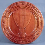 circular  wooden plaque with carved depiction of an african drum encircled by a broken chain