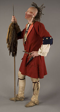 model wearing red coat, leather leggings and holding spear