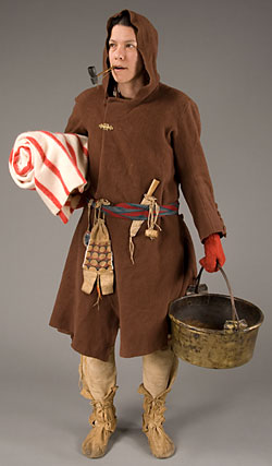 woman in brown hooded coat holding large brass kettle