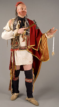 man wearing a red and gold blanket and holding an axe and string of white beads