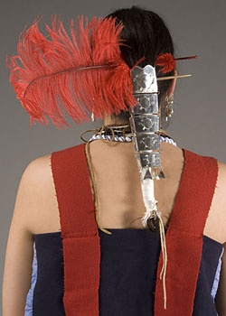back of model's head showing silver hair ornament and red feather