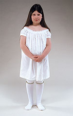 girl wearing long white linen shift and white knit stockings with garters just below the knees