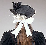close up of hat showing black ribbon band and white ostrich feather decoration