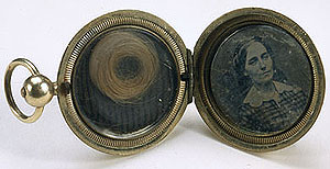 close up of round gold locket with photograph of a man in one side and a lock of hair in the other