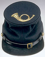 close up of dark blue, flat-topped cap with decorative brass hunting horn on top.